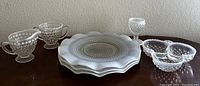Vintage Fenton bubble glass dish set including plates, cream and sugar set, and divided bowl on wood surface.