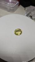 Photo showing natural lemon citrine gemstone oval cut placed on white background with visible size and color.