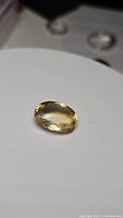 Clear view of the oval cut natural golden citrine gemstone showing its golden yellow color and surface facets.