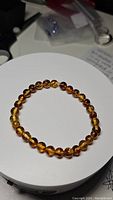 Photo showing round polished piebald amber beads of the stretchy bracelet laid flat on a white circular surface.