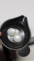 Two round white moonstone cabochons, about 11mm each, shown in a black dish to display flash and color.