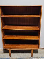 Front view of wooden bookcase showing four shelves and wear on surfaces