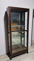 Front view of the five shelf curio cabinet showing wood frame and glass shelves inside.