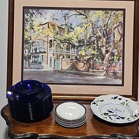 Overview of assorted plates and bowls on wooden surface under framed painting