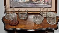 Seven assorted clear glass decorative pieces arranged on wooden table; Waterford crystal identified at front left.