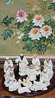 Full set of white porcelain nativity figurines including baby Jesus, Mary, Joseph, three Wise Men, shepherd, angel, and animals arranged in a circle