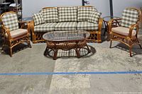 Full view of the six piece rattan furniture set showing sofa, two armchairs, coffee table, and side tables.