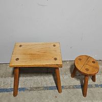 Photo showing both wooden stools, a rectangular stool with four legs and a smaller round stool with three legs