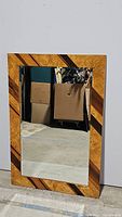 Front view of rectangular mirror showing wood frame with natural grain and geometric dark wood accents.