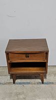 Front view of vintage wooden nightstand with single drawer and open shelf below.