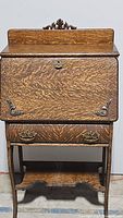 Front view of the vintage secretary desk showing wood grain, carvings, and hardware.