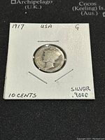 Obverse side of 1917 US Mercury Dime showing Liberty Head with winged cap, on coin holder showing date and condition.