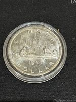 Reverse side of the 1963 Canadian silver 1 dollar coin showing the canoe with two voyageurs and 'CANADA 1963 DOLLAR' inscription.