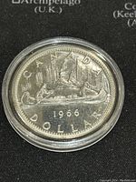 Reverse side of the 1966 Canadian Silver One Dollar Coin featuring a canoe scene with paddlers and inscriptions.