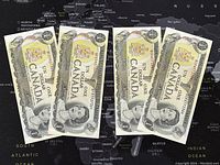 Four Canadian one dollar banknotes laid out on a map background. The banknotes show the portrait of Queen Elizabeth II and 'ONE DOLLAR CANADA' text, featuring detailed security and design elements typical of 1973 series notes.