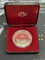 Silver coin in red velvet display case with a maple leaf emblem inside the lid.