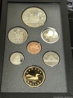 Front view of the 7 coins in the display case showing Canadian dollar, half dollar, quarter, dime, nickel, and cent coins.