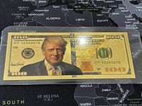 Front view of gold novelty bill in protective sleeve on map background