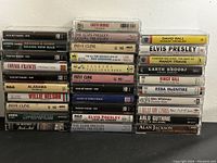 Photo of all 31 cassette tapes stacked in two columns, showing titles and artist names, condition appears good to great.