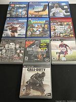 PS4 and PS3 video game cases laid out with visible titles and cover art, showing both platforms' game discs in good to great condition.