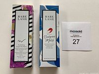 Photo of boxed Babe Lash Enriching Liquid Eyeliner and Plumping Lip Jelly side by side showing packaging design.