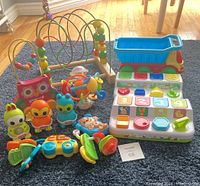 Photo of all toys together on dark blue rug showing assortment of sensory and shape sorting toys