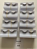 Top-down view of 10 sets of false eyelashes in white trays with rubber bands, showing different style numbers including 2107, 2507, 2515, 2508, 2506, 2514.