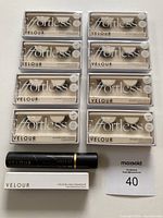 Photo showing eight pairs of Velour Effortless false lashes in packaging, a black Velour lash adhesive tube, and a white boxed Lash & Go adhesive liner, all brand new.