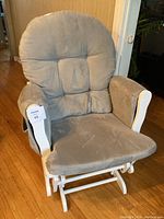 Front view of grey glider rocking chair showing cushioned seat and backrest with white wooden frame.