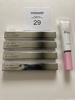 Four boxed Judy Doll Curling Iron Mascaras laid out alongside one Etude Dr. Mascara Fixer tube with white base and pink cap.