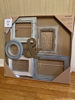 Full view of Pier 1 Imports multi-photo wooden picture frame in packaging showing distressed paint finish and decorative ampersand.