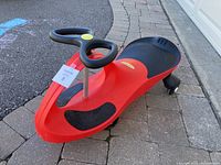 Red PlasmaCar ride-on toy car angled view showing steering wheel and footrests.