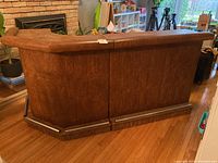 Front view of vintage two-piece bar showing padded top edges, embossed wood panels, and metal foot rails.