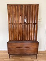 Front view of walnut tall dresser showing fluted double doors over single drawer