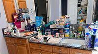 Wide view showing countertop full of assorted personal care and bathroom hygiene products including liquid soaps, lotions, and cleaning sprays.