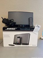 Bose SoundDock Series speaker dock, remote control, power adapter, and original box displayed on table.