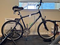 Side view of blue Giant Sedona mountain bike with black Wahoo Kickr Snap smart trainer behind and tire pump near front wheel.