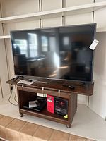 Front view of LG LCD TV on wooden stand with TV tuner and CD player visible on shelf