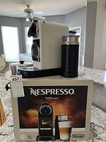 Front three-quarter view of machine and Aeroccino frother on original Nespresso box