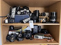 Wide view of wooden shelf with cameras, lenses, case, flash and accessories