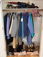 Closet view showing mixed jackets in assorted colors on hangers, boots on floor in boxes