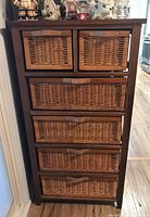 Front view of the wood framed cabinet with six wicker drawers and leather style pulls.