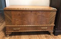 Front view of vintage wooden cedar chest with diamond inlay, brass drawer handles, and splay feet.