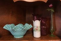 Photo shows all five items on wooden shelf: blue hobnail bowl, two cranberry glass vases, white Christmas vase, and green stem vase with pink flower.