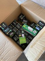 Open cardboard box showing boxes of MaxLite light bulbs, mix of LED and CFL shapes.