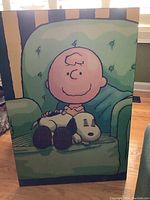 Full view of the Charlie Brown and Snoopy wall plaque, showing the characters sitting on a green armchair.