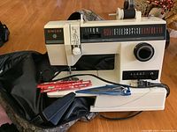 Singer sewing machine with Aero crochet needles and Solingen scissors beside it on a wooden floor