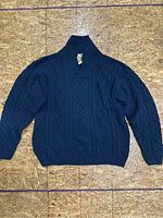 Front view of dark blue merino wool cable knit sweater showing shawl collar and button detail.