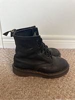 Side profile of one black leather Dr. Martens boot with visible creasing and signature yellow stitching on sole.