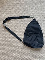 Full view of the black Eddie Bauer sling bag showing the shape and adjustable strap.